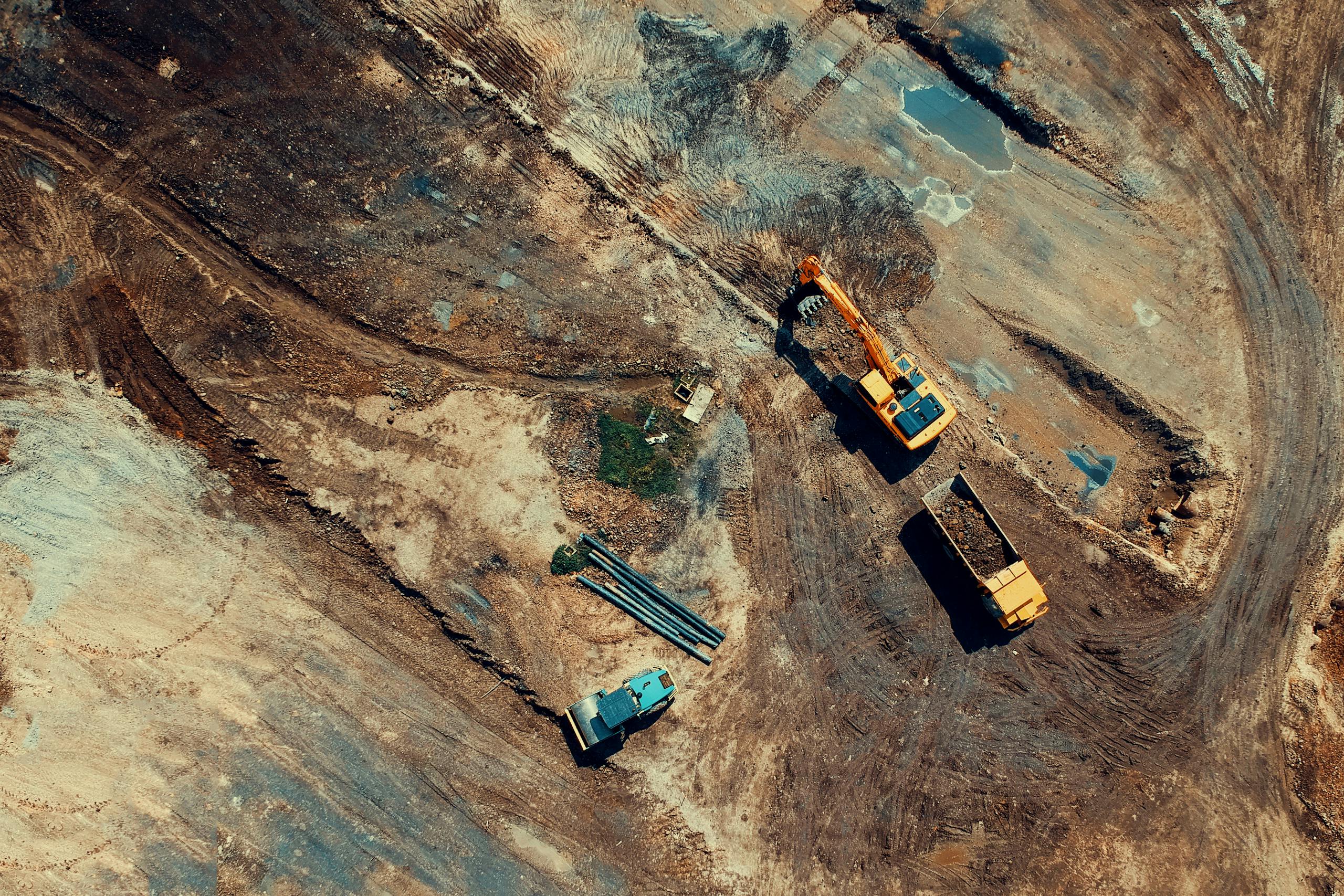 Aerial view of a construction site featuring heavy machinery and trucks, displaying industrial activity.