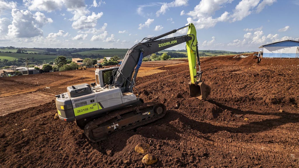 Aerial view of an excavator at a construction site in Londrina, Paraná, with clear skies and rural landscape.